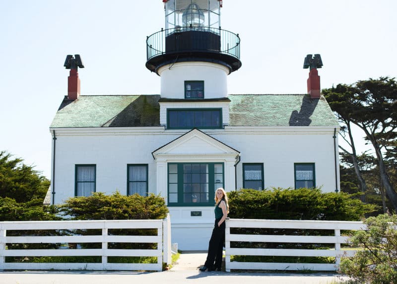 standing in front of a lighthouse in carmel california taking senior pictures
