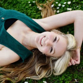 senior in college taking portraits in the grass with flowers