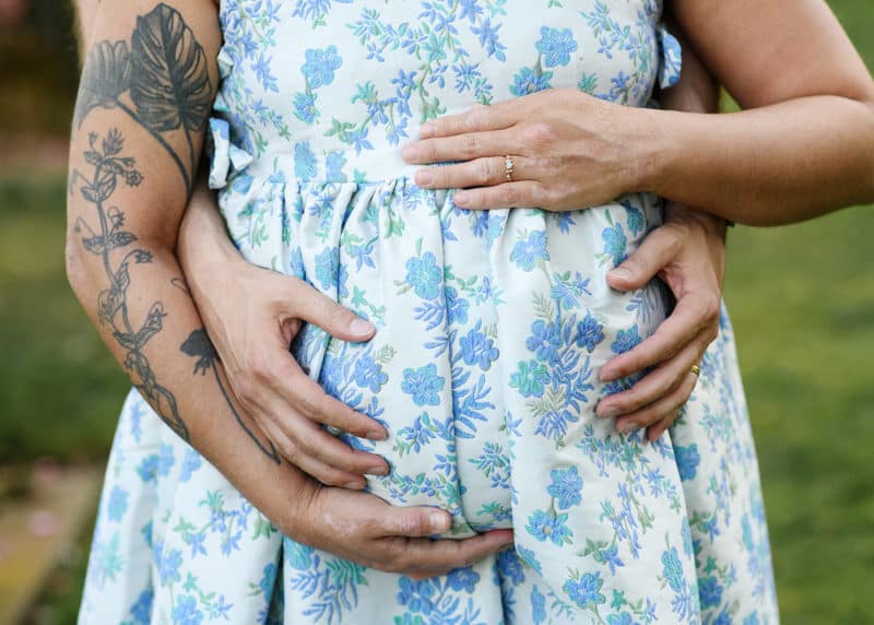 man and woman holding pregnant belly in a garden in sacramento california