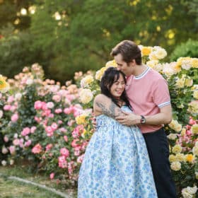 pregnant couple hugging together in a rose garden during spring in sacramento california