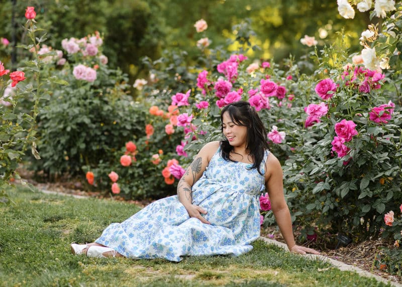 pregnant woman sitting in a rose garden during spring in sacramento california