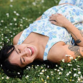 pregnant woman laying in a field of flowers and smiling in sacramento california