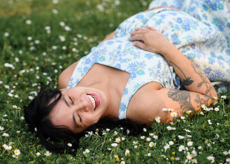 pregnant woman laying in a field of flowers and smiling in sacramento california