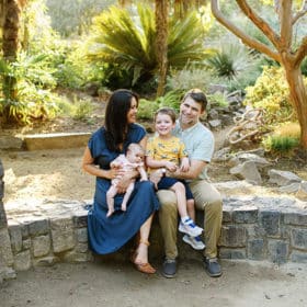family of four sitting on a rock wall laughing together in sacramento california