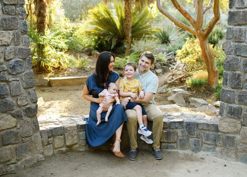 family of four sitting on a rock wall laughing together in sacramento california