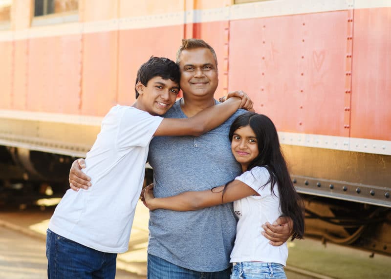 dad hugging son and daughter in front of a train in folsom california