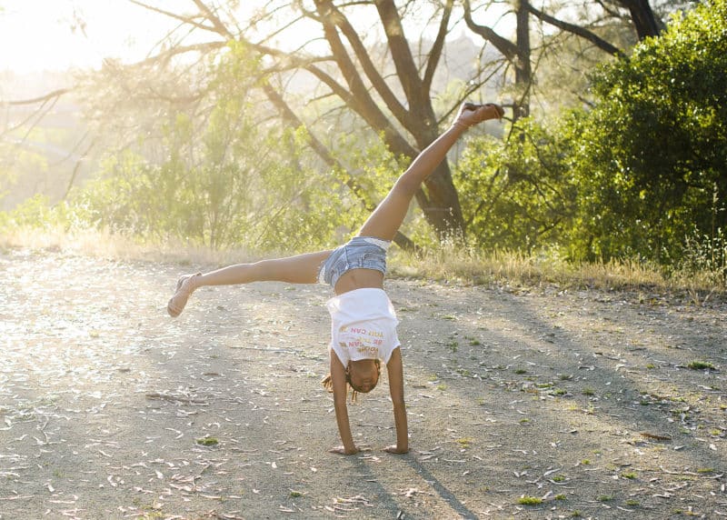 young girl doing a cartwheel in the spring with natural light shining