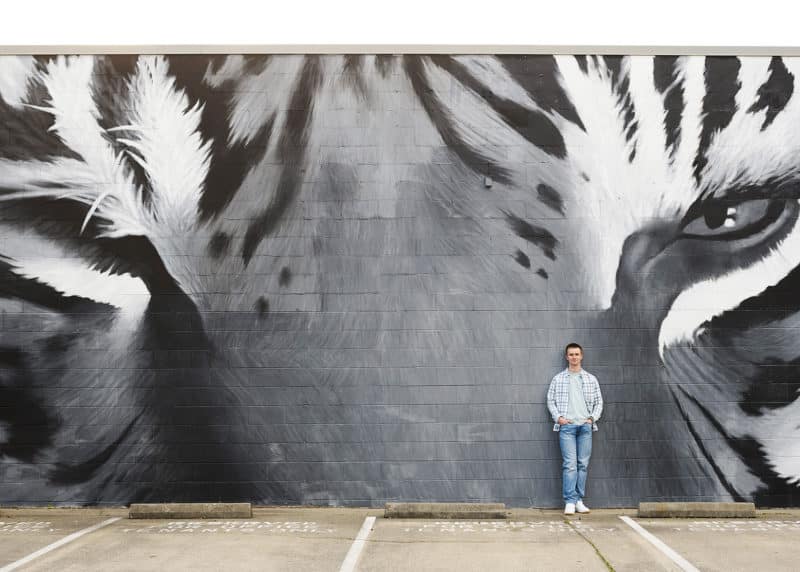 taking senior portraits in front of a mural of a tiger in downtown sacramento california