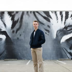 senior in high school taking portraits in front of a tiger mural in downtown sacramento california