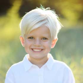 young boy wearing a white collared shirt smiling at the camera during family photos in davis california