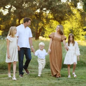 family of five holding hands and walking together toward the camera during golden hour family photo session in davis California