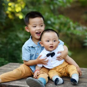 young brothers sitting on a table hugging during family photos in davis california