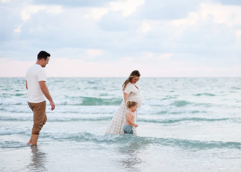 mom and son walking in the ocean during sunset on vacation in florida, dad following behind