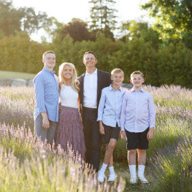 family of five standing in the middle of a lavender field smiling together and hugging