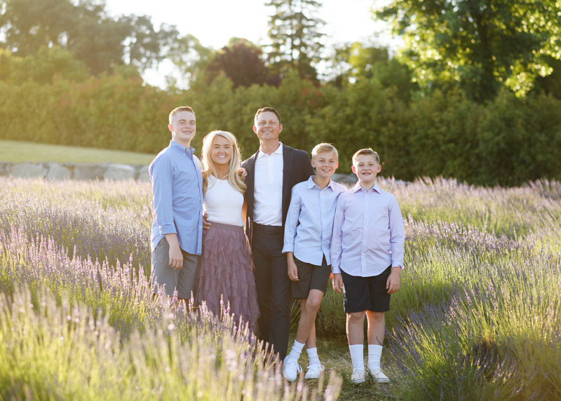 family of five standing in the middle of a lavender field smiling together and hugging