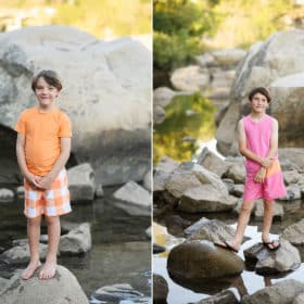 young boys standing on rocks and smiling at the camera in pink and yellow swimsuits during family photo session at folsom lake