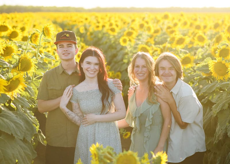 mom with three grown kids standing a field of sunflowers during family photography session in dixon california