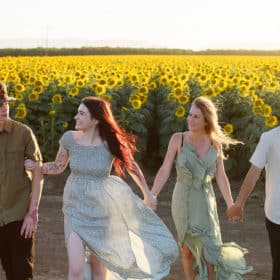 holding hands and walking toward the photographer during family photo session in the sunflower fields of dixon california