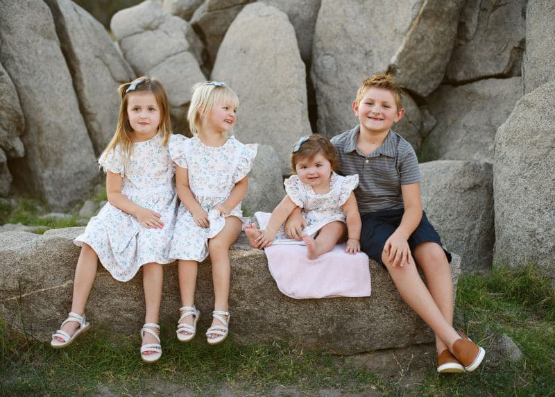 four young siblings sitting on a rock in granite bay california during family photography session