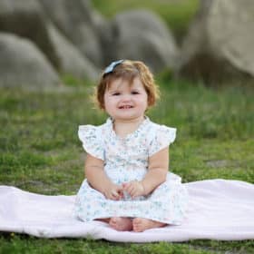 baby girl sitting on a pink blanket in the grass during family photography session in granite bay california