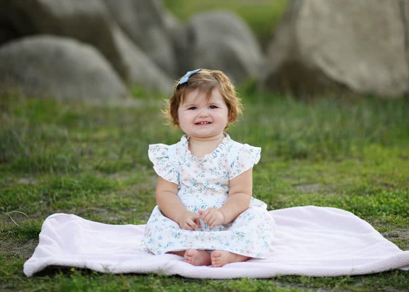 baby girl sitting on a pink blanket in the grass during family photography session in granite bay california