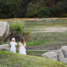 two young sisters holding hands and walking toward the water during family photography session in granite bay california