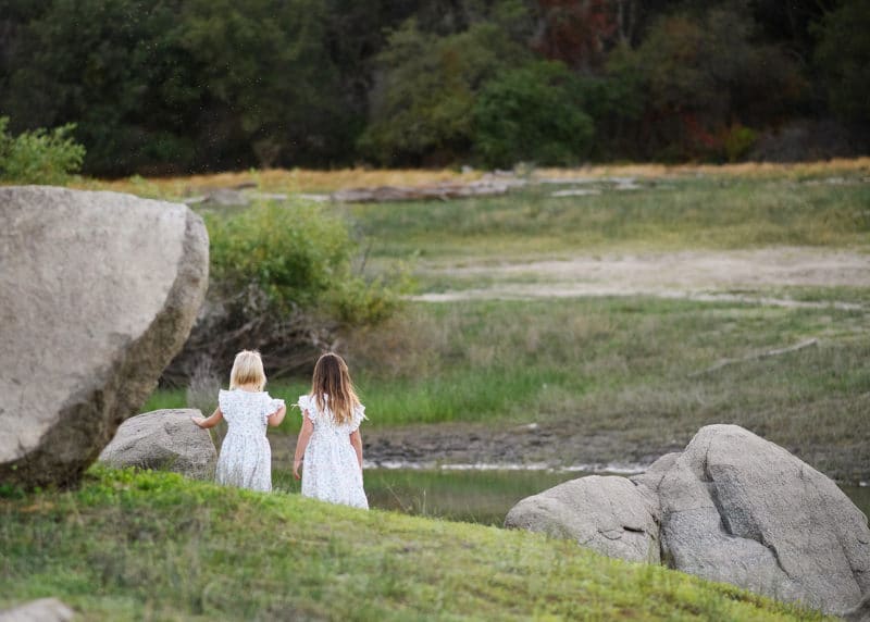 two young sisters holding hands and walking toward the water during family photography session in granite bay california