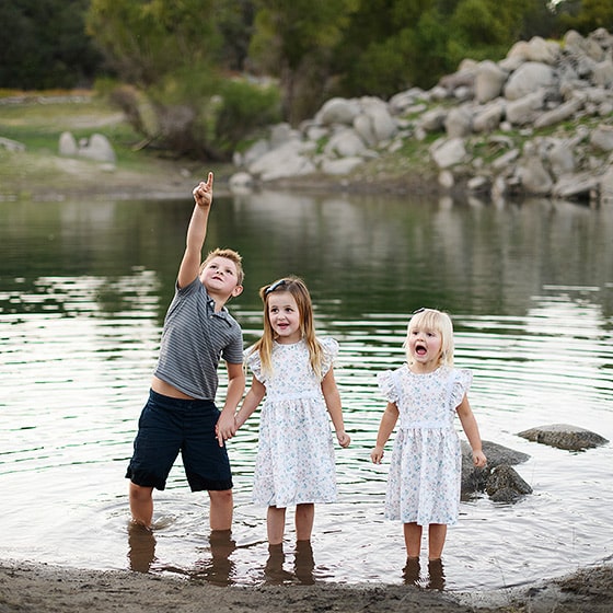 three siblings standing in the water during family photography session in granite bay california