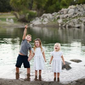 three siblings standing in the water during family photography session in granite bay california