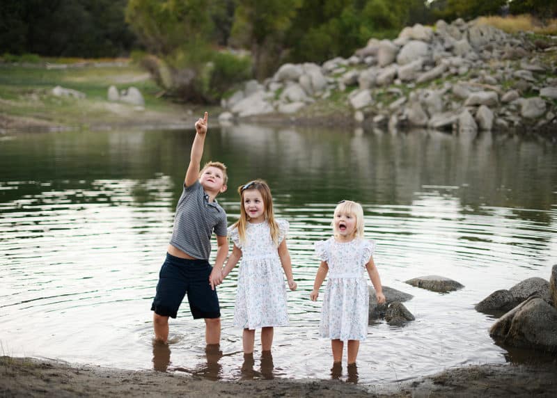 three siblings standing in the water during family photography session in granite bay california