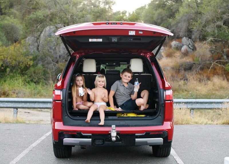 three young siblings sitting in a car having snacks looking at the photographer in granite bay california