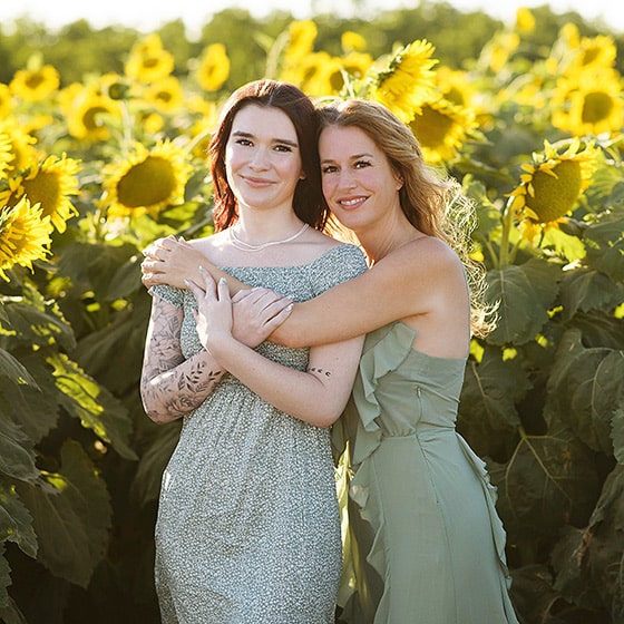 mom hugging daughter in the middle of a sunflower field in dixon california