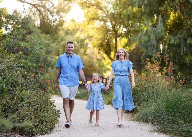 family of three walking toward the photographer in a park in davis california