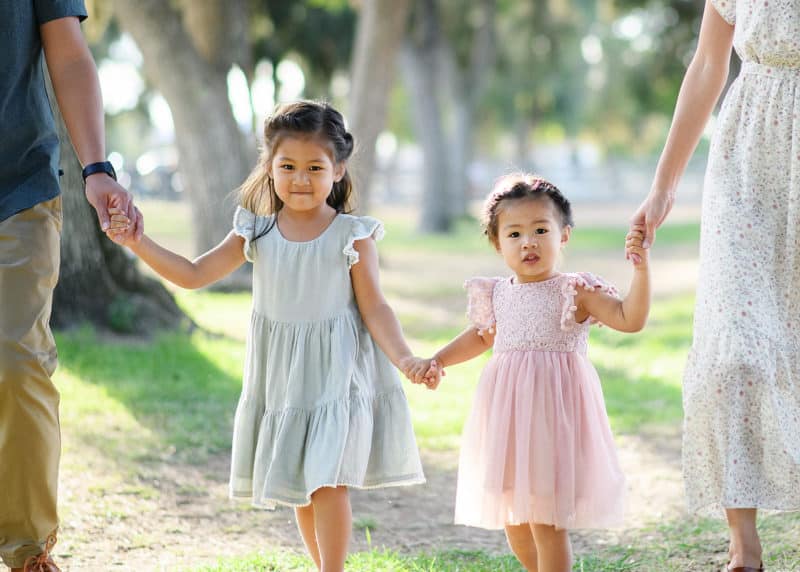 Sacramento photographer -- two young sisters holding hands with mom and dad and walking toward the camera