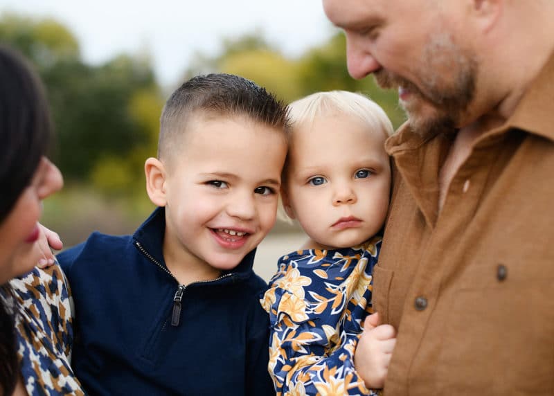 sacramento photographer with a family of four taking photos of kids while mom and dad hold them