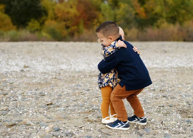 young brother and sister hugging by the river in sacramento california with photographer jill carmel