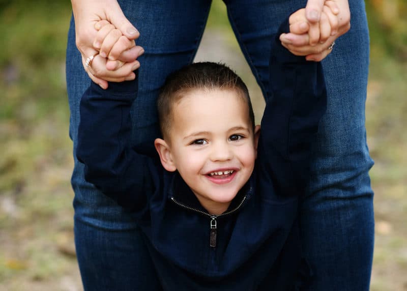 young boy smiling at a camera during fall family photos with sacramento photographer jill carmel