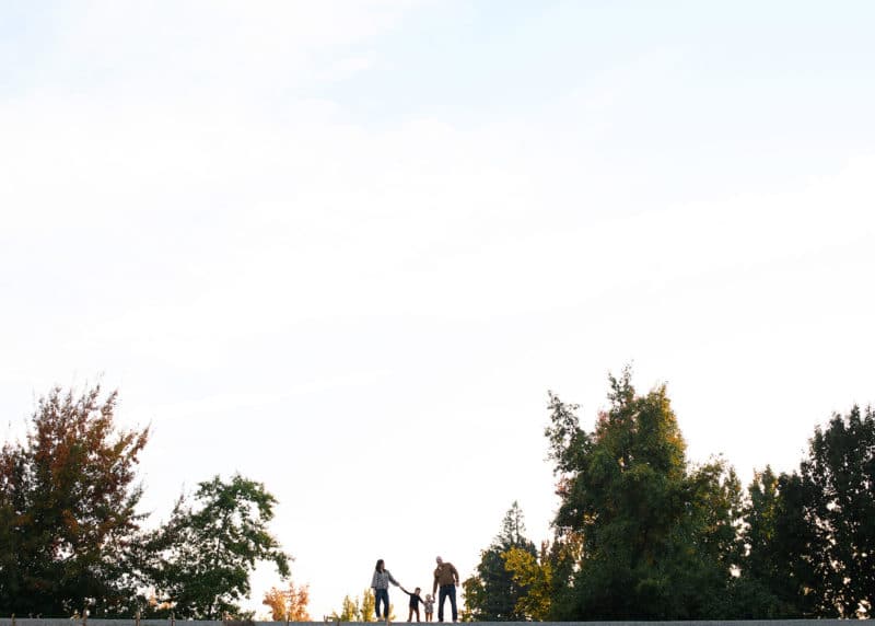 family of four holding hands on a hill during fall family photos in sacramento california