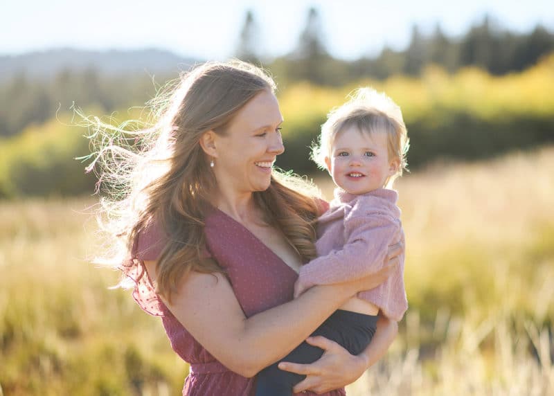 mom holding young daughter in the fall golden sunlight at lake tahoe california