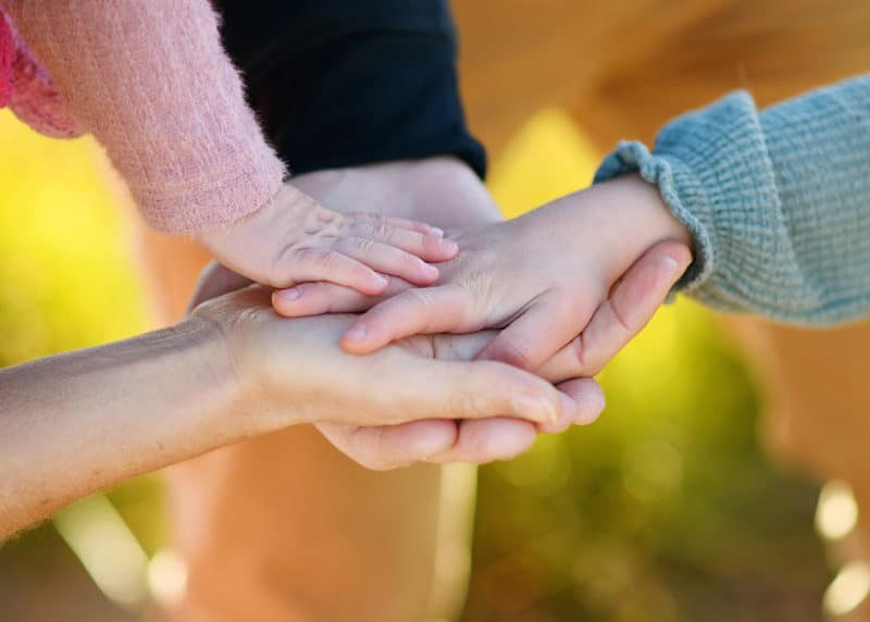 family of four putting hands on top of one another with a lake tahoe family photographer