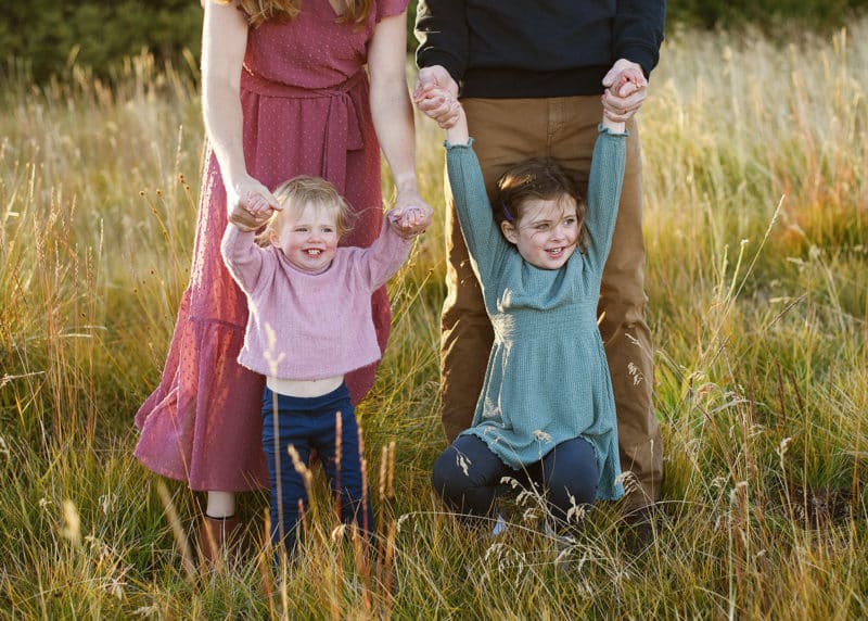 two young girls holding hands with mom and dad during family photography session in lake tahoe california