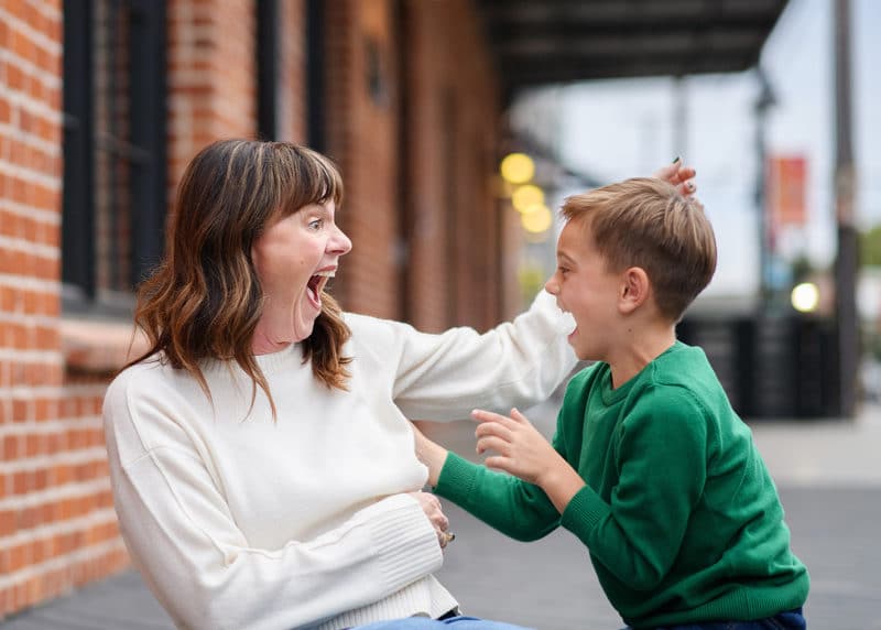 mom and young son making silly faces and smiling during family photos in downtown sacramento california