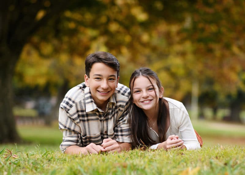 brother and sister laying on the grass during fall family photos with sacramento photographer 