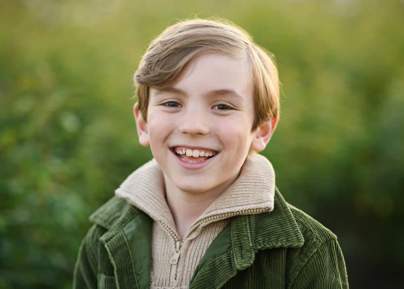 young boy looking at the camera and laughing during fall family photos in yuba city california