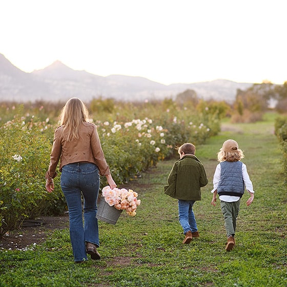 mom holding a basket of roses and walking with two young sons while yuba city photographer takes pictures