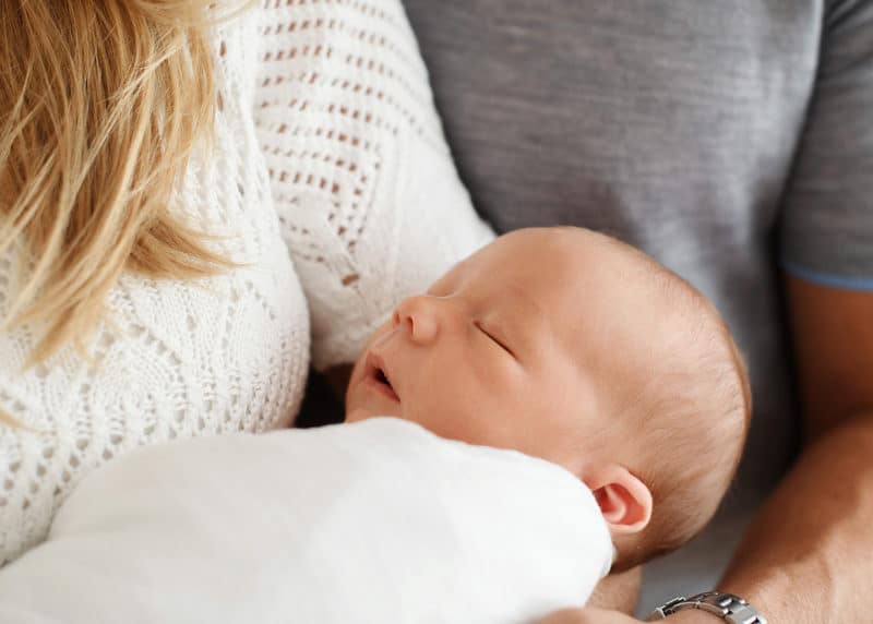 newborn baby sleeping in mom's arms during a newborn photo session in the studio