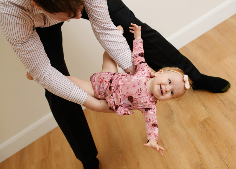 dad playing with one year old girl during family photo session in the studio