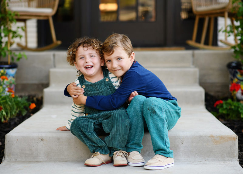 two young boys hugging on front steps of family home during photo session with sacramento photographer jill carmel