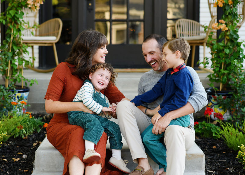 family of four sitting on front steps of home during at-home family session in sacramento california