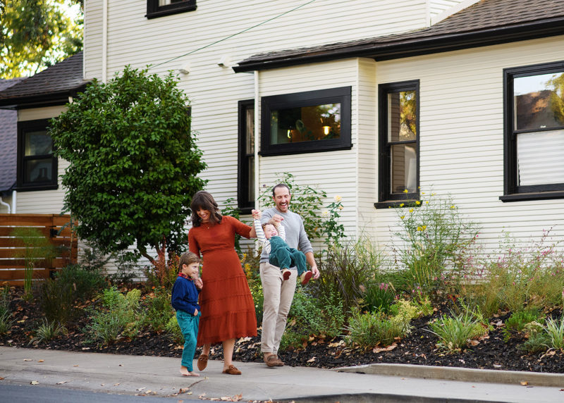 family of four walking together in front of family home in sacramento california with photographer jill carmel